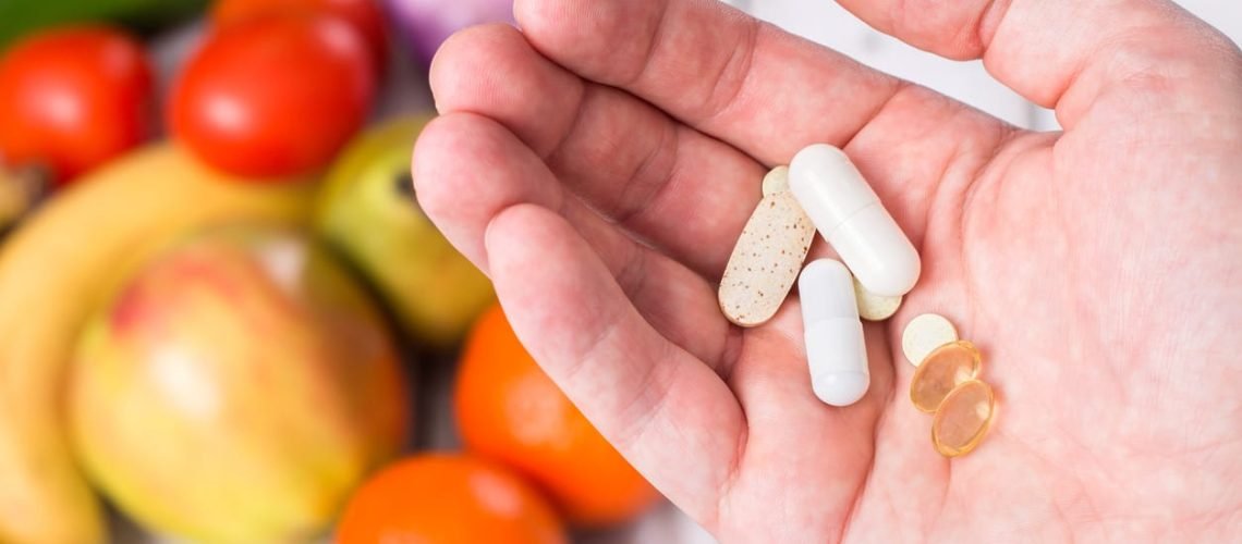 Hand with dietary supplements on fruity background Hand with dietary supplements on fruity background
